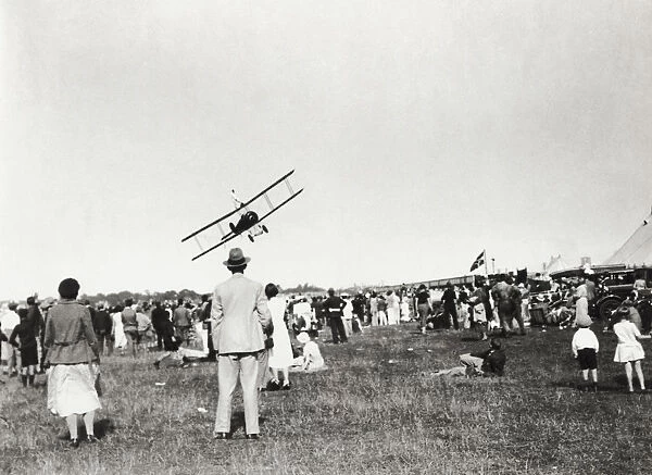 A Crowd of People Watching a Biplane Aircraft Flypast wi?