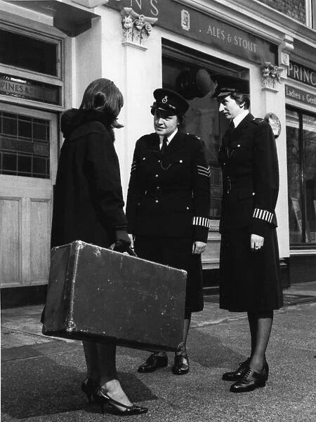 Two women police officers and woman with suitcase