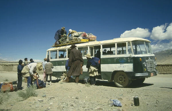 20018193. TIBET Bus Bus in the countryside being loaded with goods by passengers