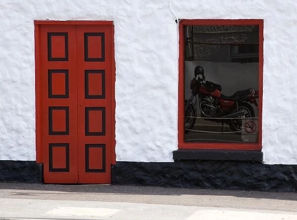 Ireland, Glenties. Reflection of a red motorcycle in a window next to a bright red door