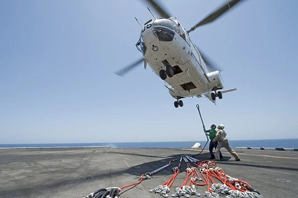 Airmen attach a cargo hook to an SA-330J Puma helicopter