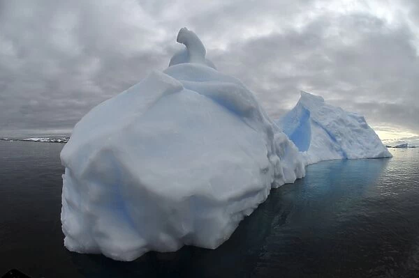 Floating iceberg with grey sky and black sea, Antarctica