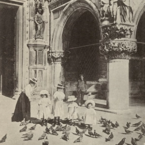 Girls feeding the pigeons close to St. Marks Basilica
