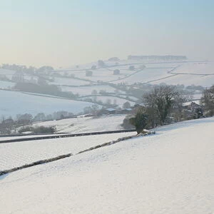 Snow covered hillside pastureland, arable fields and bare trees in winter, Tadwick, Bath and Northeast Somerset, England, United Kingdom, Europe