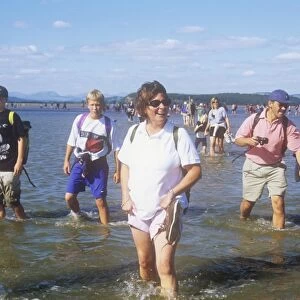 People crossing Morecambe Bay at low tide on a sponsored walk being led by Cedric Robinson. Cedric is the Queens offical guide to the treacherous sands of Morecambe bay. Lancashire