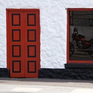 Ireland, Glenties. Reflection of a red motorcycle in a window next to a bright red door