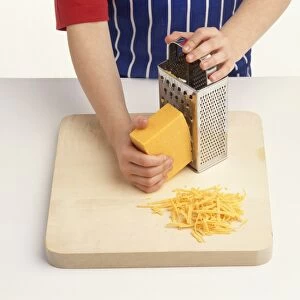 Child grating cheese onto chopping board