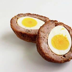 Scotch egg, sliced in two showing hard-boiled egg and sausage meat in breadcrumbs, close-up