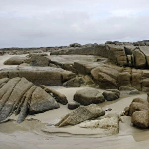 Granite rocks in tidal zone of sandy beach at the Altanic coast of Donegal on a foggy day, Ireland