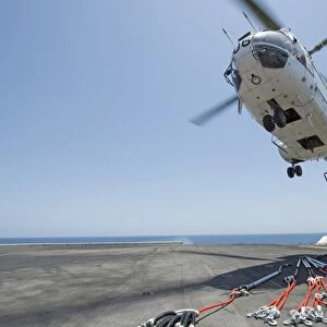 Airmen attach a cargo hook to an SA-330J Puma helicopter