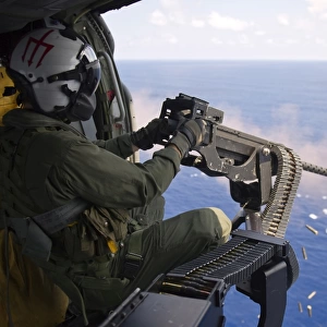 Naval Aircrewman fires a. 50-caliber machine gun from a MH-60S Knighthawk