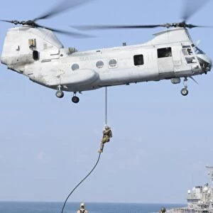Soldiers fast rope from a CH-46E Sea Knight helicopter onto amphibious transport