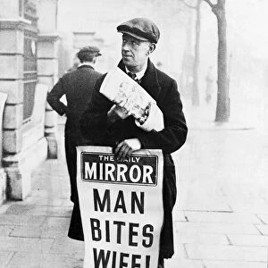 Daily Mirror newspaper vendor carrying advertising hoarding with Man Bites Wife headline