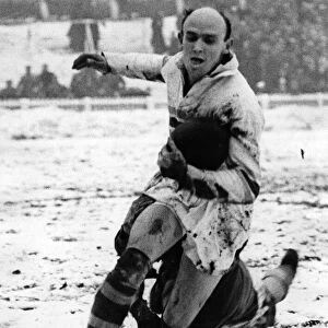 Rugby player Bevan Brian evades a tackle whilst in action in the snow