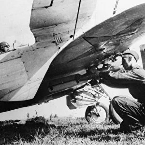A Soviet pilot sits at his controls while bombs are attached to his aircraft