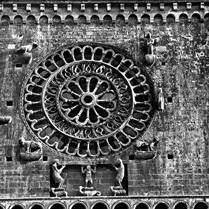 Middlr rose window of the Cathedral of Assisi. At its corners, the symbols of the four evangelists and at the base, three telamons. Under the rose window the hanging gallery and small arches